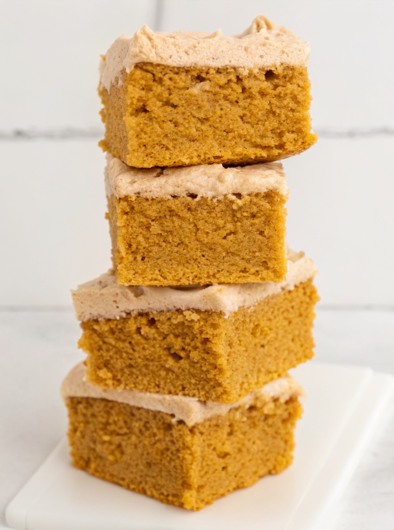Sliced pumpkin spice cake with cinnamon cream cheese frosting on rustic wooden board