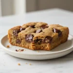 Delicious close-up of a perfectly baked Chocolate Chip Cookie Bar revealing its soft, chewy texture and melted chocolate.